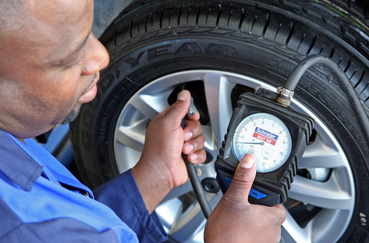 Tyre mechanic checking tyre pressure for slow puncture
