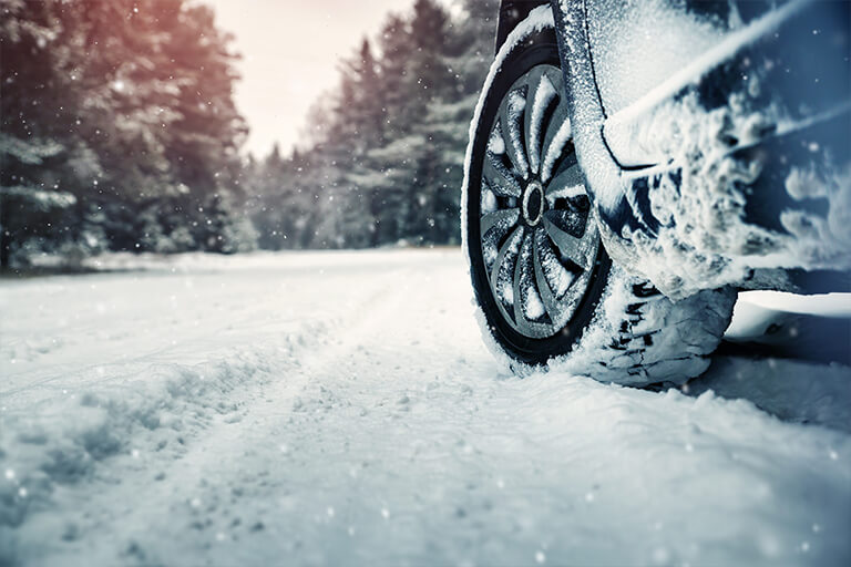 Car travelling in snow during winter, fitted with Goodyear Winter Tyres