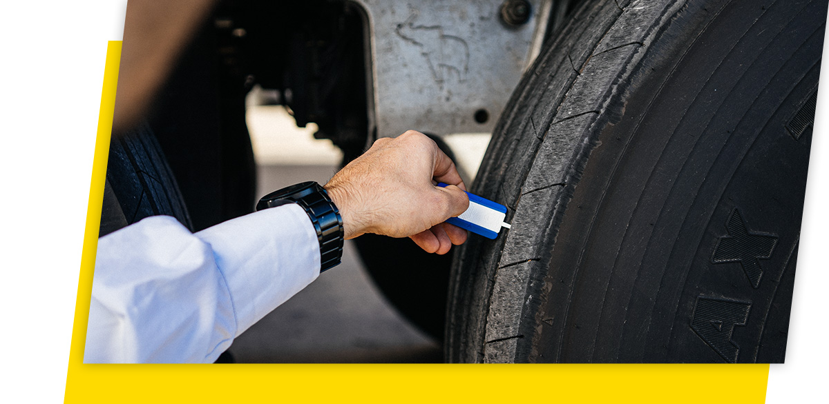 Una persona mide la profundidad de la banda de rodadura del neumático