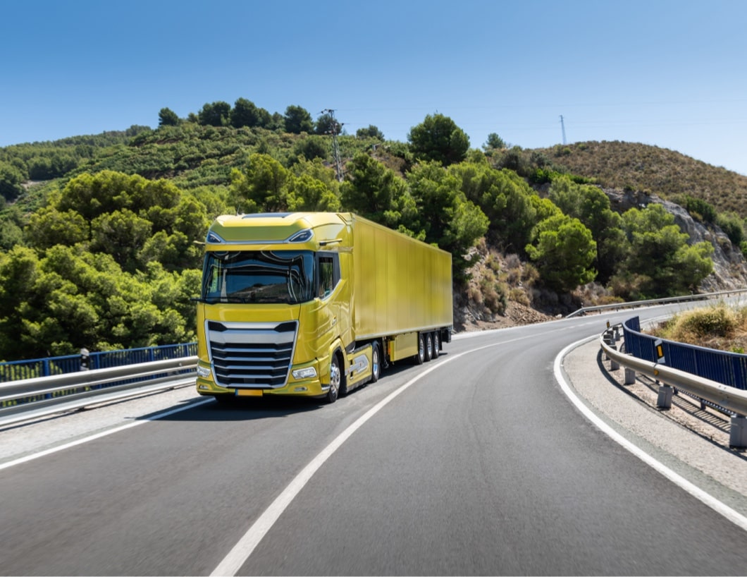 Camion jaune roulant sur une route avec paysage