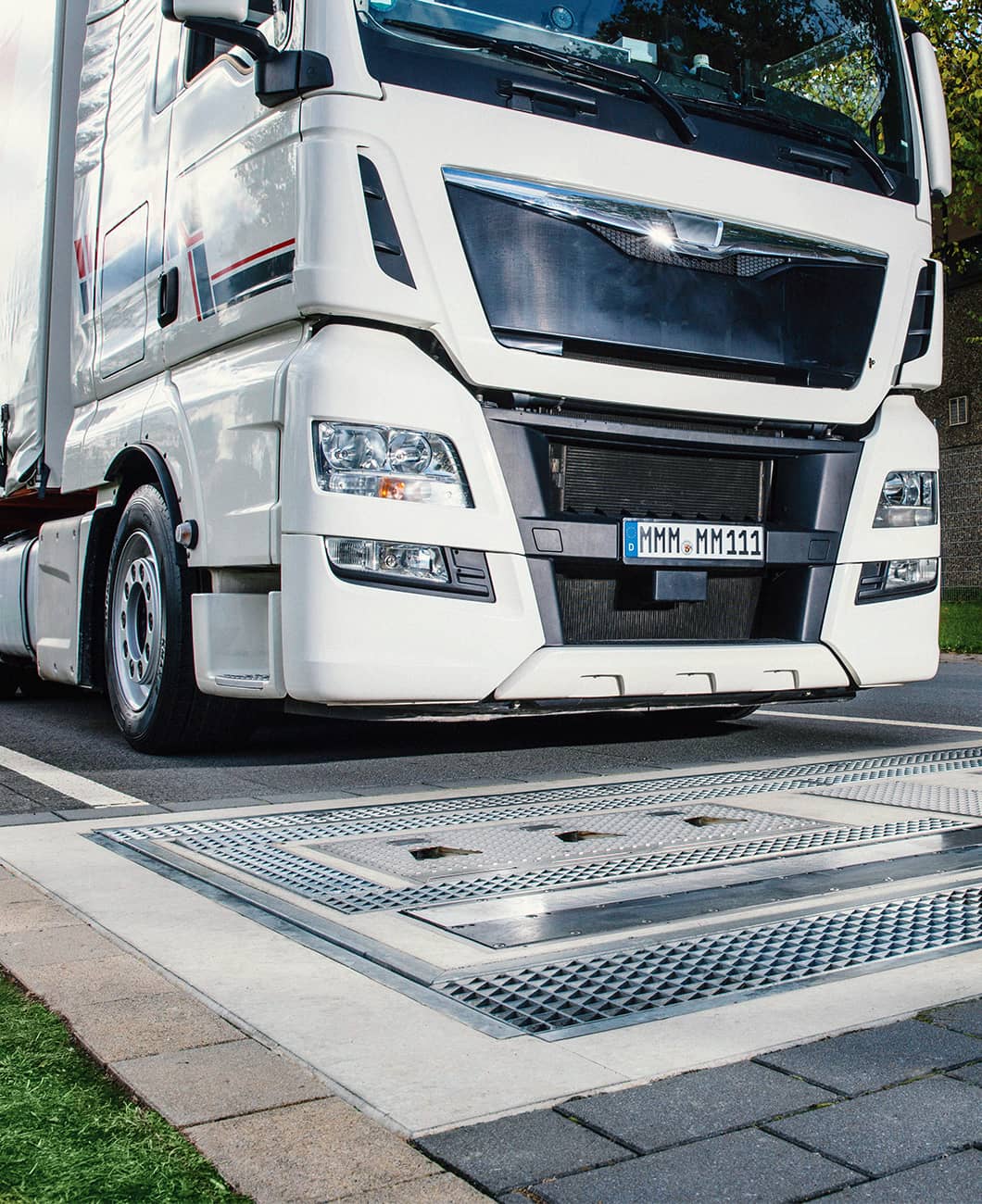White truck driving over ground-mounted sensor of drive over reader